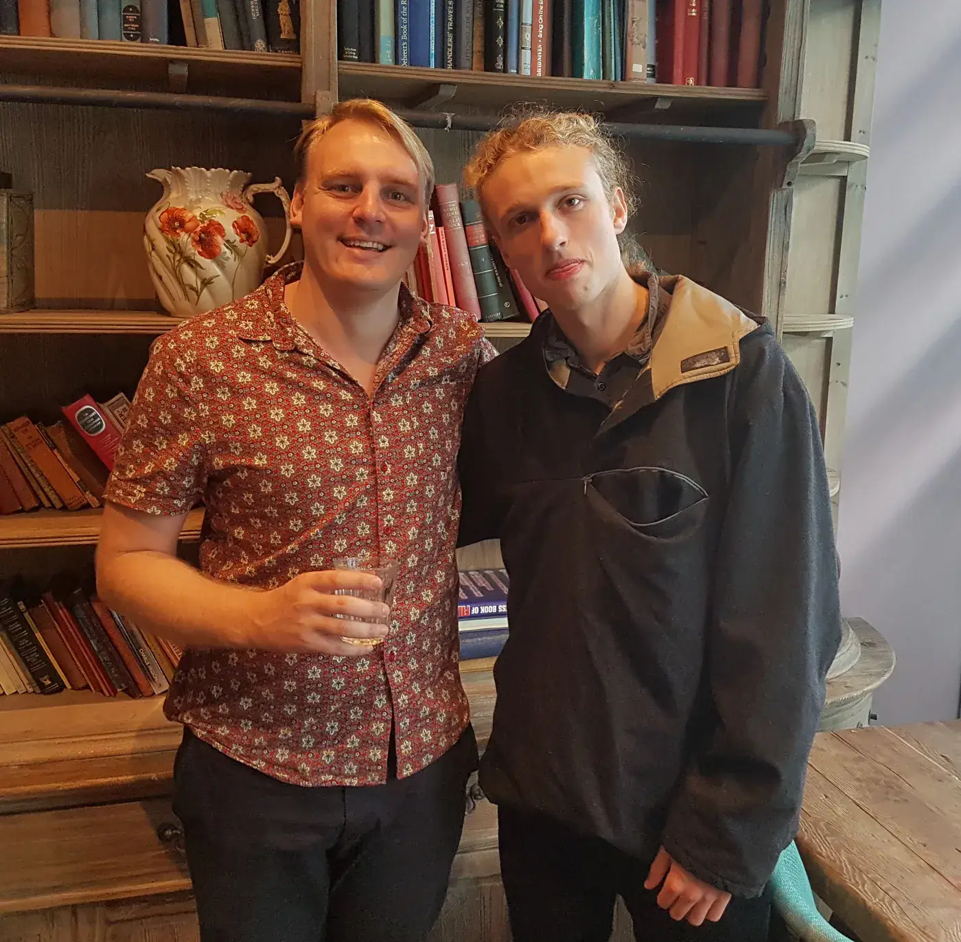 Two Stop Holding Back members standing by bookshelves